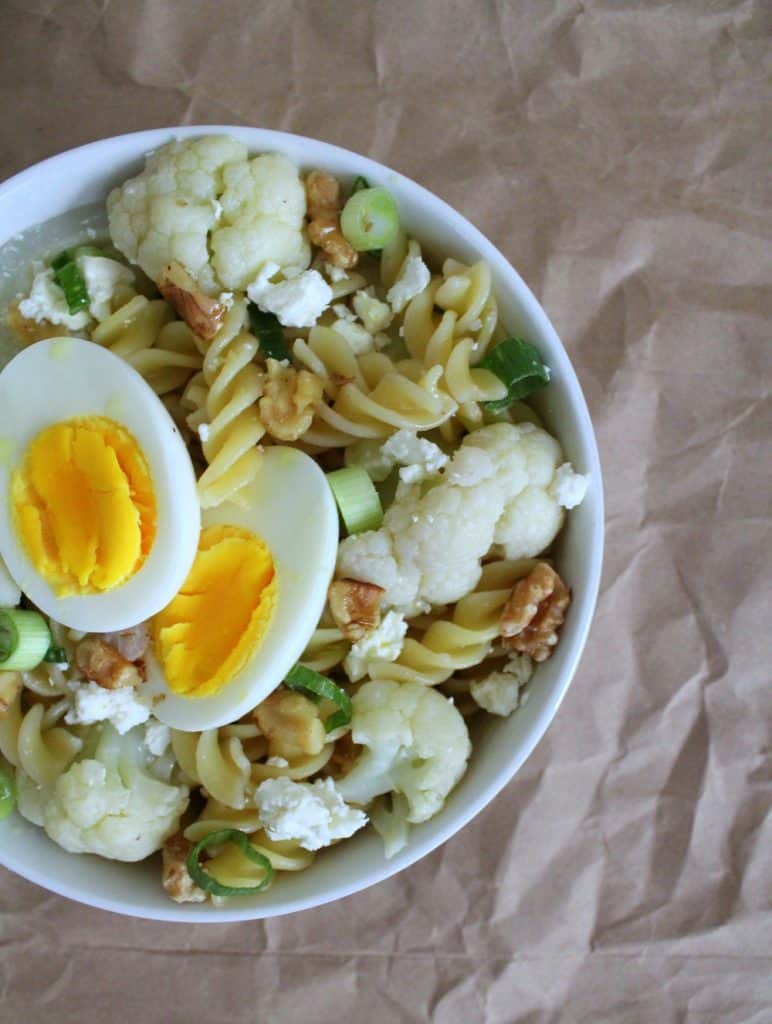 This weeknight cauliflower pasta with pecans and feta is also topped with a hardboiled egg, and a generous sprinkling of scallions.