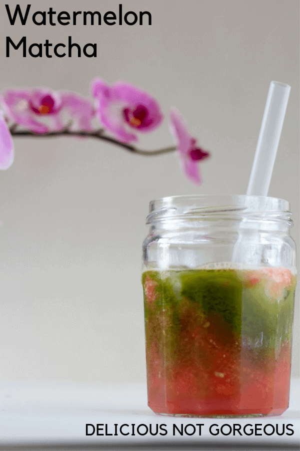 Pink watermelon puree and bright green matcha layered in a mason jar with straw. Purple orchid in background
