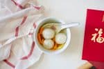 White dumplings (tāng yuán) in a clear broth with sweet potato and ginger.