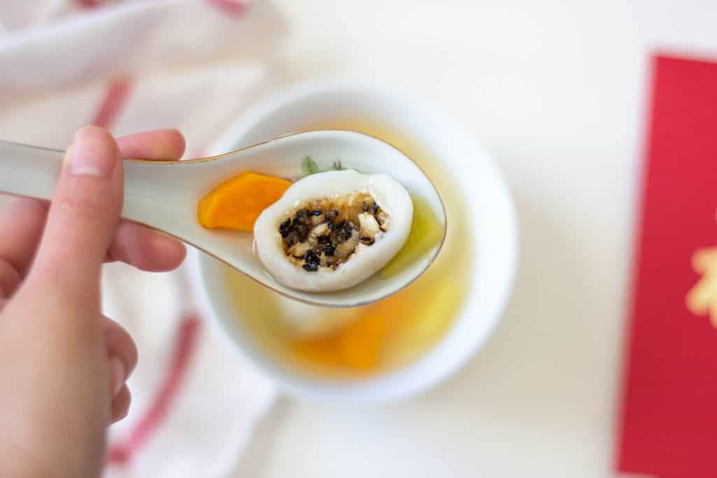 Inside of a chewy white dumpling (tāng yuán in Mandarin), with flecks of black sesame seeds and toasted coconut.